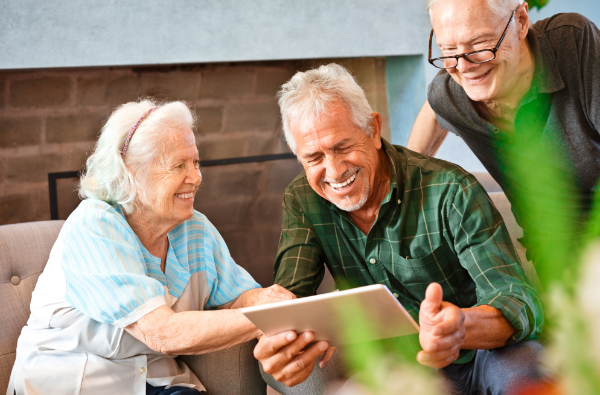 Happy elderly friends using a gadget