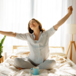 Happy woman enjoys morning coffee in the bedroom with houseplant